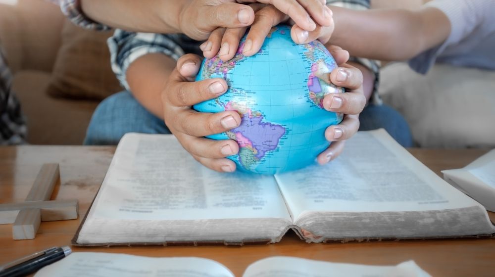 hands on a globe sitting on a Bible