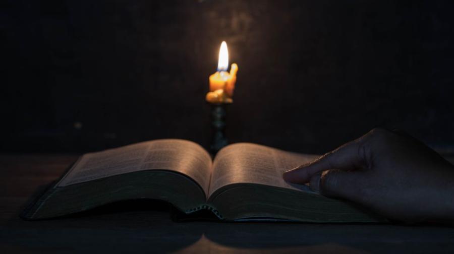 lit candle with open bible