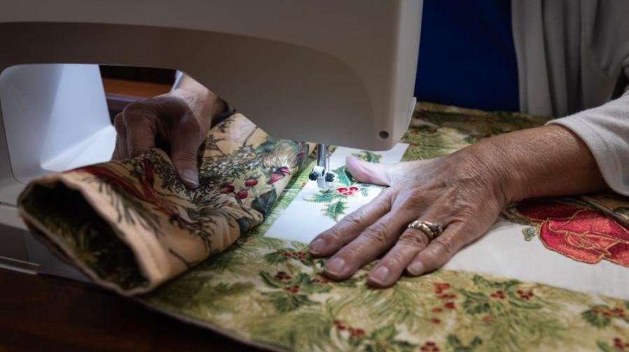 a hand using machine to quilt