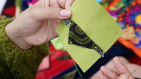 hands holding quilt square and needle